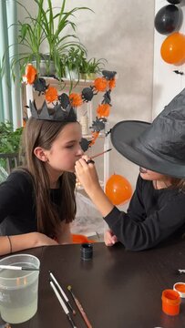 Children paint their faces and dress up. A girl in a witch costume for Halloween is having a black scary party, a Halloween Grimm.