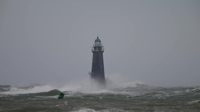 Hurricane high winds causing waves to crash against a lighthouse slow motion