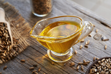 Milk thistle oil in a glass jug with Carduus marianus seeds