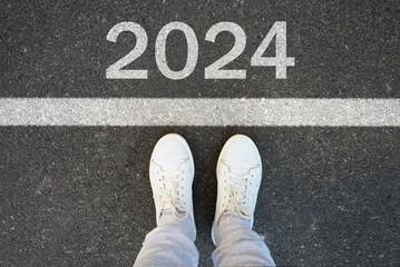 Female legs in white sneakers stand on the asphalt with the inscription 