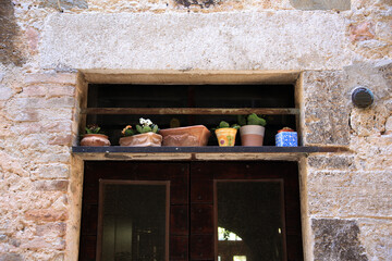 A niche in the stone wall, above the old door, decorated with potted plants, Umbria, Italy