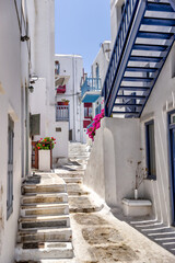 Mykonos, Greece - July 21, 2023: Colorful buildings and flowers in the labyrinthine streets of Mykonos Greece
