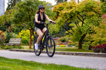 Fit Caucasian Woman riding an Electric Bicycle on a trail in Stanley Park, Downtown Vancouver,...