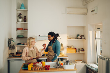 A happy multicultural couple is cooking at trying out a new recipe at home.