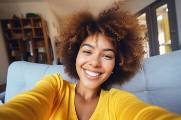 Happy afro American woman relaxing on the sofa at home. Girl taking selfie picture with smartphone