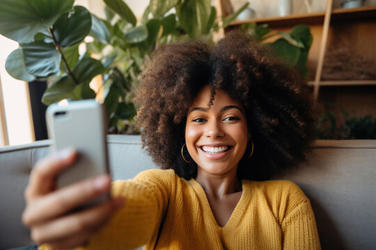Smiling girl taking selfie picture with smartphone lying on the couch
