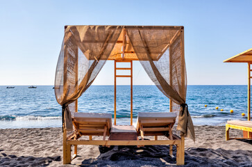Fira, Greece - July 20, 2023: Palapas and beach chairs on the island of Santorini in Greece
