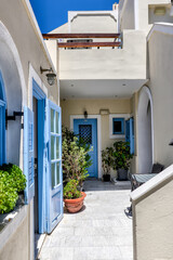 Fira, Greece - July 20, 2023: Colourful flowers and building entrances in the town of Fira on the...