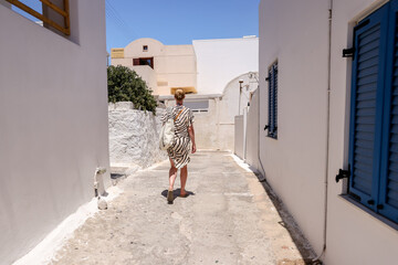 Fira, Greece - July 20, 2023: A woman walking and taking pictures along the walkways in the town of...