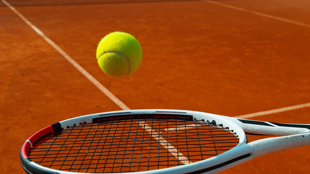 Bouncing tennis ball on tennis racket, clay court, freeze motion