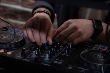 A DJ in a nightclub at the control panel adjusts the music. Music is playing, creating an...