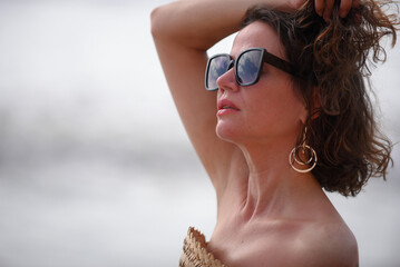 young relaxed woman on the beach model summer coastline light clothing lipstick sunglasses hair and...