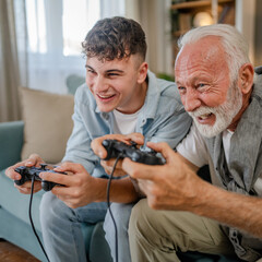 teenager male and his grandfather senior man play console video game