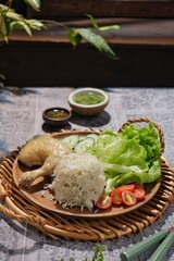 Nasi Hainan or Hainan chicken serving on wooden table with tofu soup, tomato, letuce and cucumber. It suitable for diet meal for lunch.