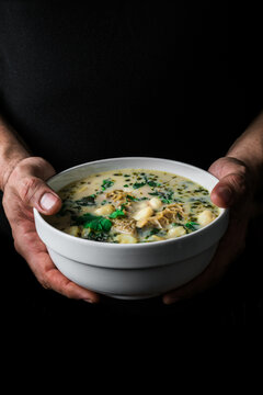 Vertical image of a man's hands with a Patasca soup.