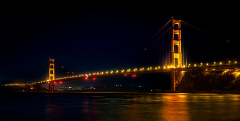 Golden Gate Bridge at night with a reflection on the bay.