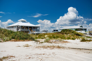 Houses on stilts along the Atlantic Ocean. Blue sky with snow-white clouds.