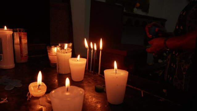 Persona sin rostro encendiendo Velas candelas veladoras de cera parafina encendidas en iglesia templo cat&oacute;lico tradici&oacute;n fe esperanza oraci&oacute;n y meditaci&oacute;n