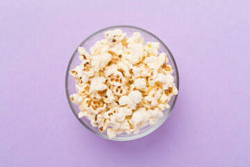 Tasty popcorn in bowl on color background, top view