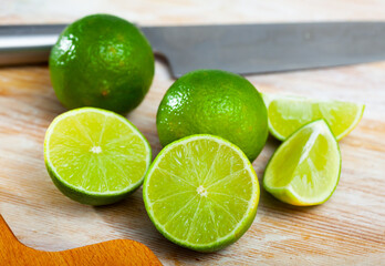 Ripe lime and knife on wooden cutting board