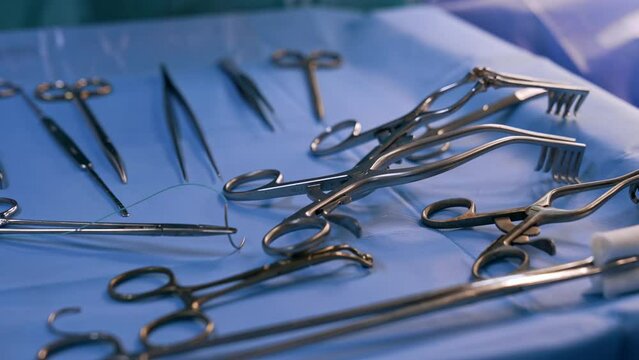 A set of medical tools prepared for the operation. Instruments used at surgery on blue backdrop. Close up.