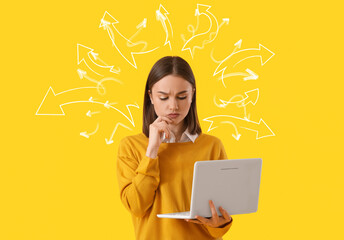 Thoughtful young woman with laptop on yellow background. Concept of choice
