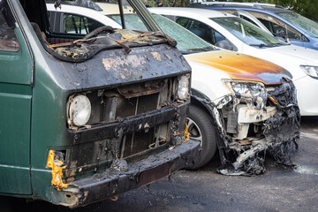 Minivan was burned in fire. Parking lot with burnt cars. Concept - transport fire insurance. Cars were damaged by flames. Automobiles with melted bodies. Charred minivan after fire. Insurance case