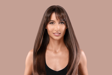 Hair styling. Portrait of beautiful woman with straight long hair on pale brown background