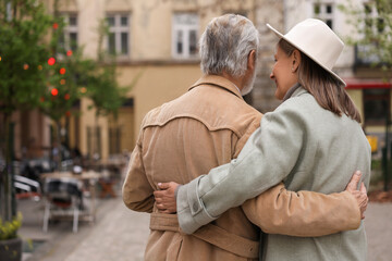 Fototapeta premium Affectionate senior couple walking outdoors, back view. Space for text