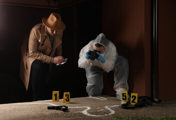 Investigator and criminologist working at crime scene outdoors in evening