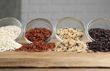 Different types of rice on wooden table, closeup