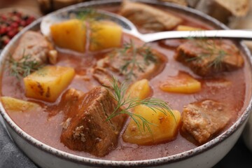 Delicious goulash in bowl on table, closeup