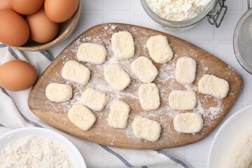 Making lazy dumplings. Board with cut dough and ingredients on white tiled table, flat lay