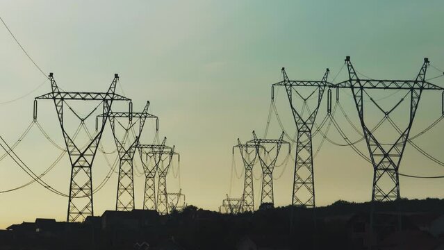 Aerial view of transmission towers with power line in the evening. Overhead power lines sending electricity country wide