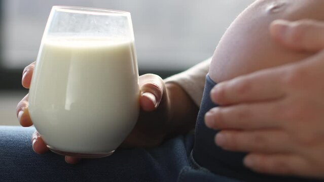 Pregnant woman drinking milk at home. Staying hydrated and consuming dairy products while pregnant. Pregnancy, milk, dairy and calcium drink concept. Food and drinks.