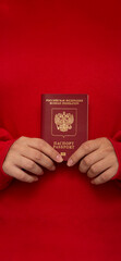 Vertical banner. Female hands hold biometric passport on bright red background. Concept of travel,...