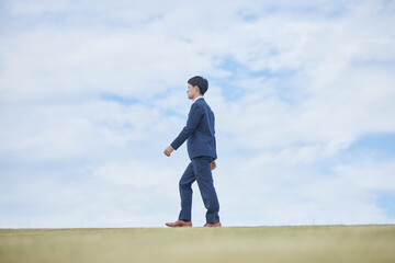 Obraz premium 青空とスーツの男性 Blue sky and a man in a suit