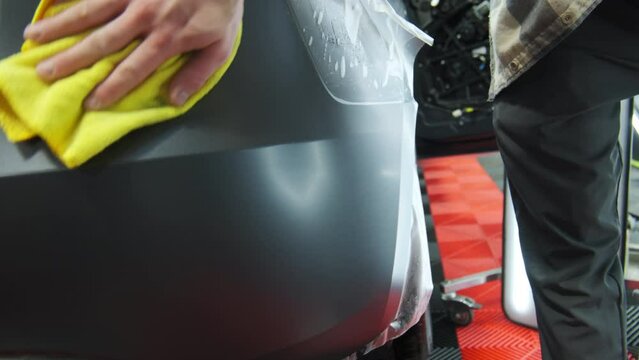 Process of applying a protective PPF film to a car. Hands of a professional applying a protective film. Closeup shot