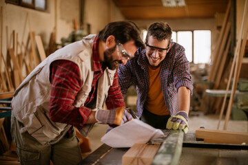 Two male carpenters working in a wood shop