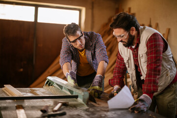 Two male carpenters working in a wood shop