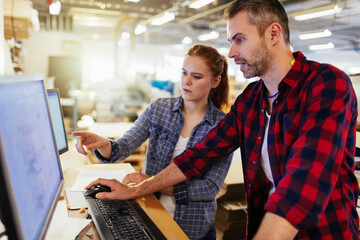 Young Caucasian colleagues working on computer in a warehouse