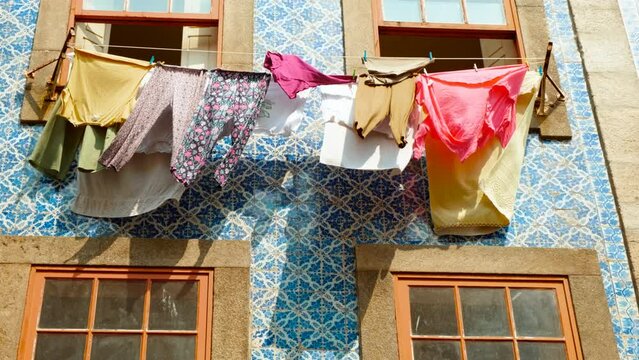 Colorful clothes hang outside a charming tiled house, adding local flair to the scenic streets of Porto, Portugal, famous for Port wine