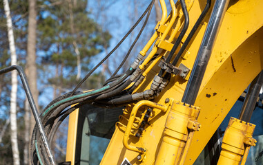 Closeup of the hydraulics hoses, pipes, fittings and cylinders on a working excavator machine.