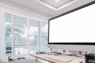 Workspace with blank screen in bright office room interior.