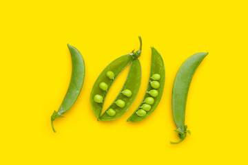 Fresh young green peas on yellow background.