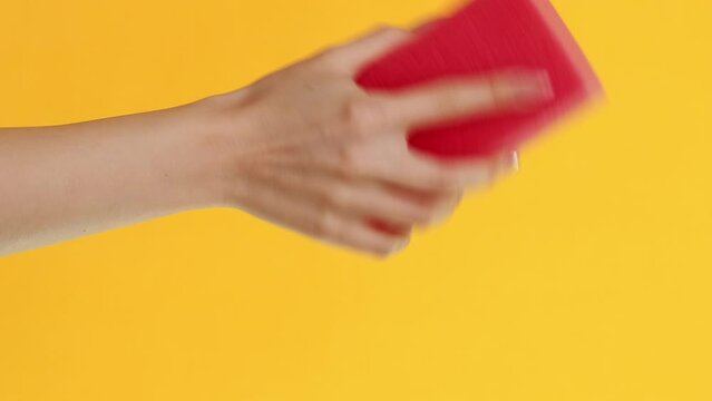 Vertical video. Cleaning tools. Dirty surface. Woman hand washing with pink household sponge wiper removing dust isolated on yellow background.