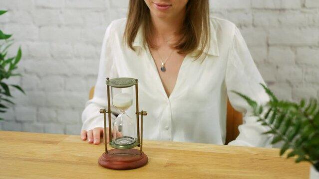 A young woman turning over an hour class egg timer to measure the passing of time