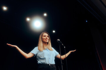 Woman Standing on a Stage Speaking on the Microphone. Motivational speaker talking about success and mindfulness to public audience 