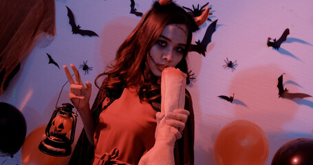 Young Asian woman is at a Halloween night party, looking at the camera, smiling.