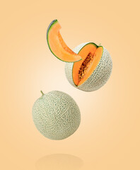 Japanese melon or cantaloupe melon with cut slice levitate isolated on orange color background.